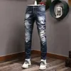 Stitchdetaljer accent Förskjutna jeans män mager fit rippad blekmedel tvättmålade cowboybyxor312x