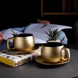فنجان القهوة الذهبي المرتفع في Wourmth مع ملعقة منزل بسيطة شاي حديثة.