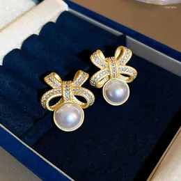 スタッドイヤリングhuitan lyデザインは、女性向けのシミュレートされた真珠付き弓をデザインしています豪華なゴールドカラーアクセサリーウェディングパーティートレンディジュエリー
